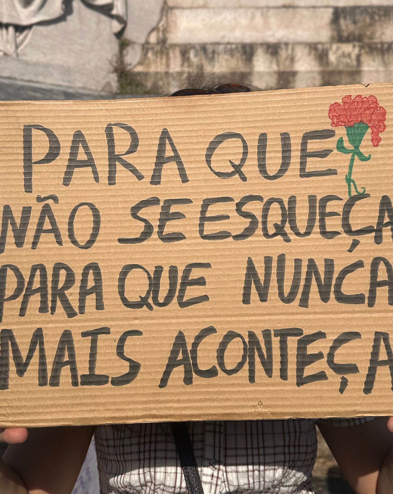 Alguém segura um cartaz com as palavras "Para que não se esqueça para que nunca mais aconteça"