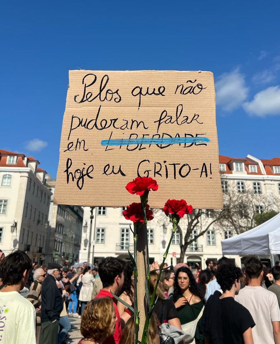 Uma pessoa segura num cartaz que diz "Pelos que não puderam falar em Liberdade hoje eu GRITO-A!"
